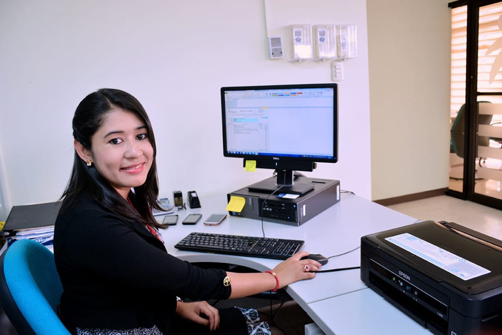 A young woman sits in front of a computer in an office.